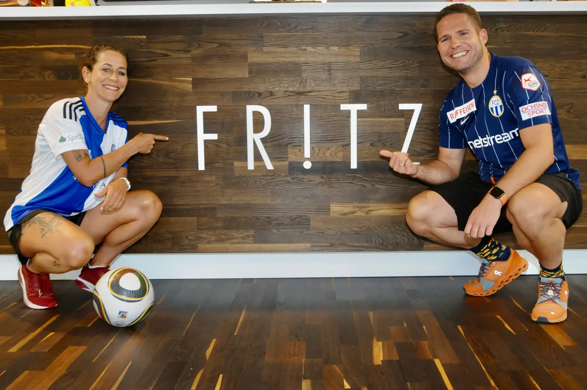 Man sieht eine Frau und einen Mann vor dem Fritz-Logo.